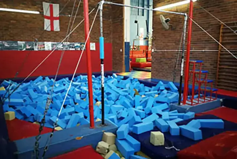 Rand Gym's foam training pit filled with blue foam blocks beneath a high bar