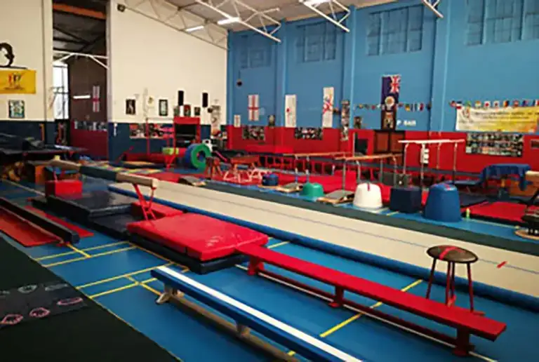 Gymnastics classes in Randburg happen in Rand Gym's main training hall, with a tumble track, balance beams, parallel bars and red safety mats