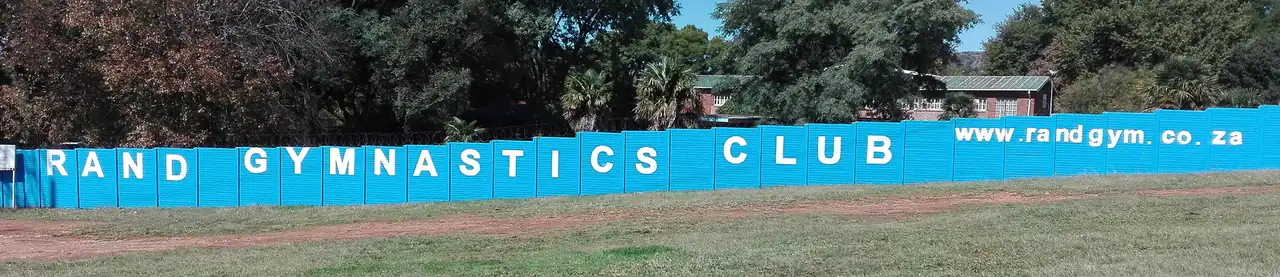 The long blue Rand Gymnastics Club wall with www.randgym.co.za painted in white letters, at Franklin Roosevelt Park